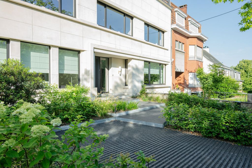 Allée d'accès en pavés drainants bordée de graminées et d'hortensias devant une maison à Verviers