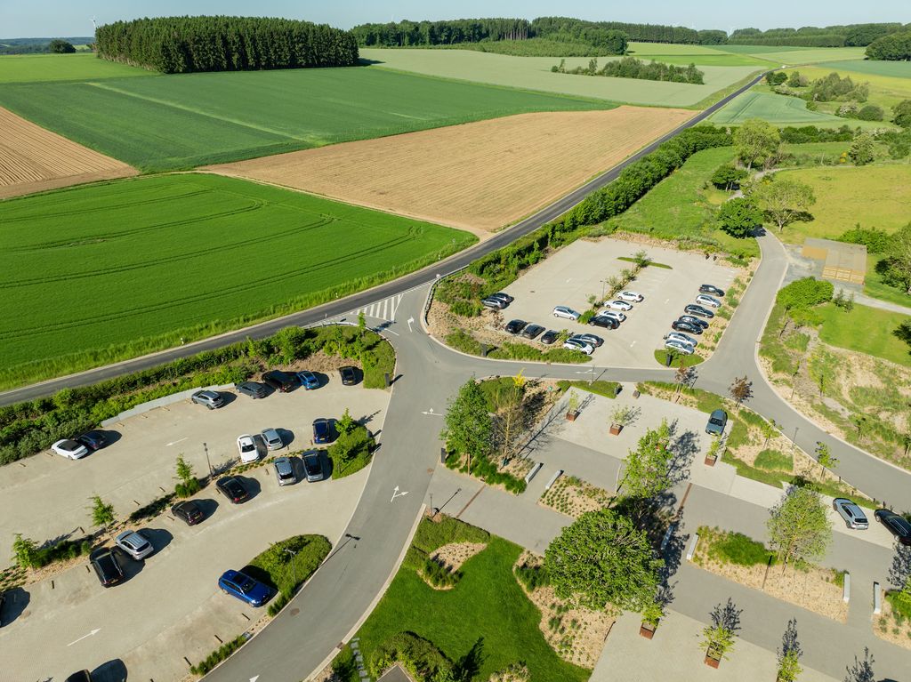 Vue aérienne du parking paysager planté d'arbres et d'îlots verts de l'Anatura Hotel à Weiswampach