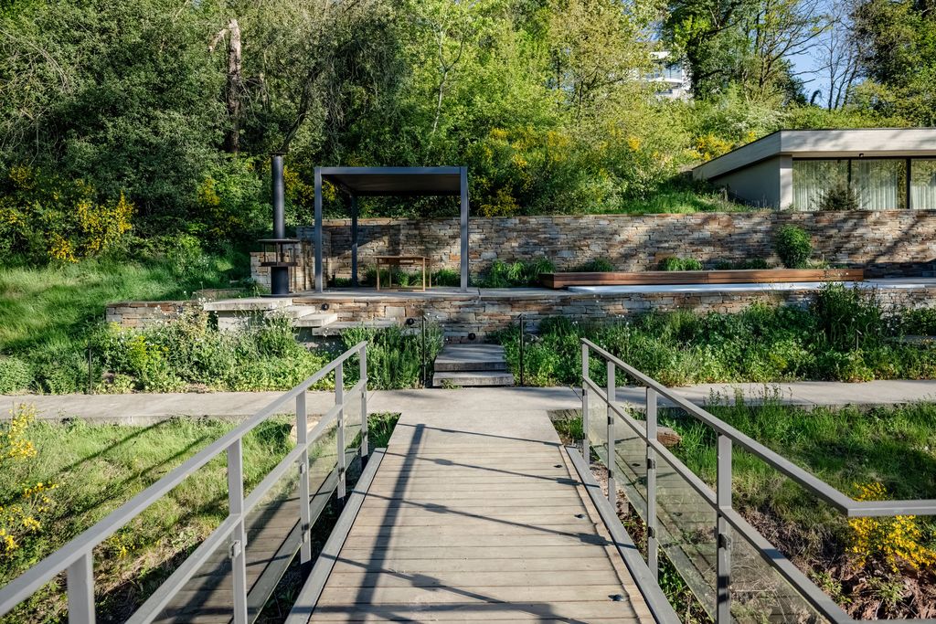 Passerelle en bois et métal menant aux terrasses d'un jardin en pente boisé