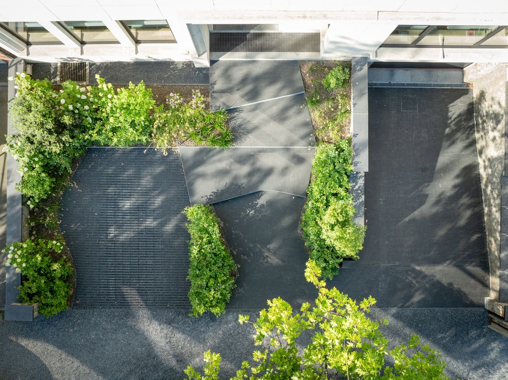 Entrée réaménagée vue du ciel : allée aux lignes courbes, place de parking perméable et massifs de graminées à Verviers
