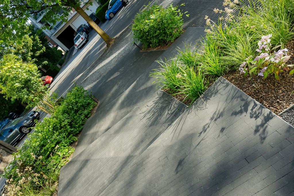 Parterres incurvés plantés de graminées et d'hortensias, découpés dans l'allée pavée, à Verviers
