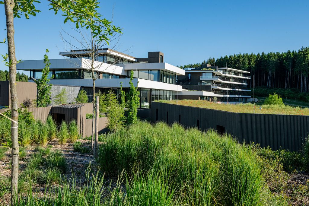 Parterres de graminées et jeunes arbres devant l'Anatura Hotel & SPA à Weiswampach