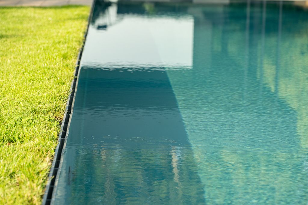Le gazon au ras de l'eau le long de la rigole de débordement de la piscine